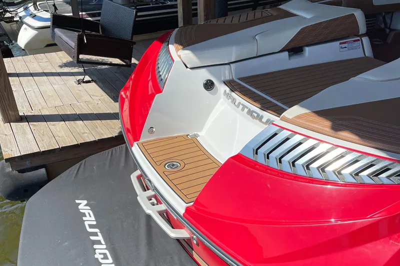 Slide: The Image of 2019 Nautique Super Air Nautique G23 Coastal Edition, red and white, docked at marina. - 2