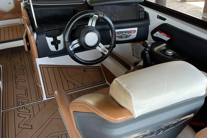 Slide: The Image of Interior of 2019 Nautique Super Air Nautique G23 Coastal Edition boat, featuring steering wheel and seating. - 8
