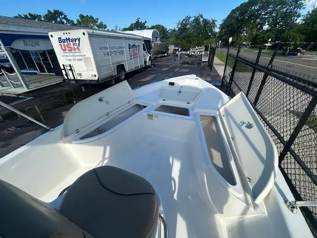 Slide: The Image of 2019 NauticStar 2140 Sport boat with open storage compartments, parked near a fence. - 11