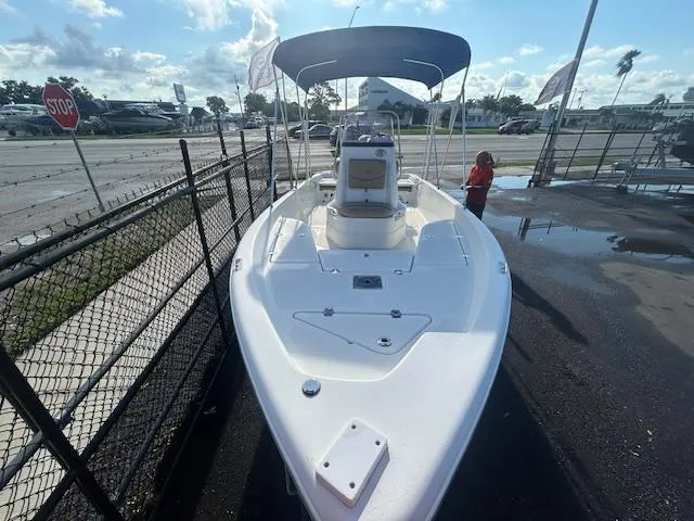 Slide: The Image of 2019 NauticStar 2140 Sport boat with canopy, parked near a fence on a sunny day. - 9