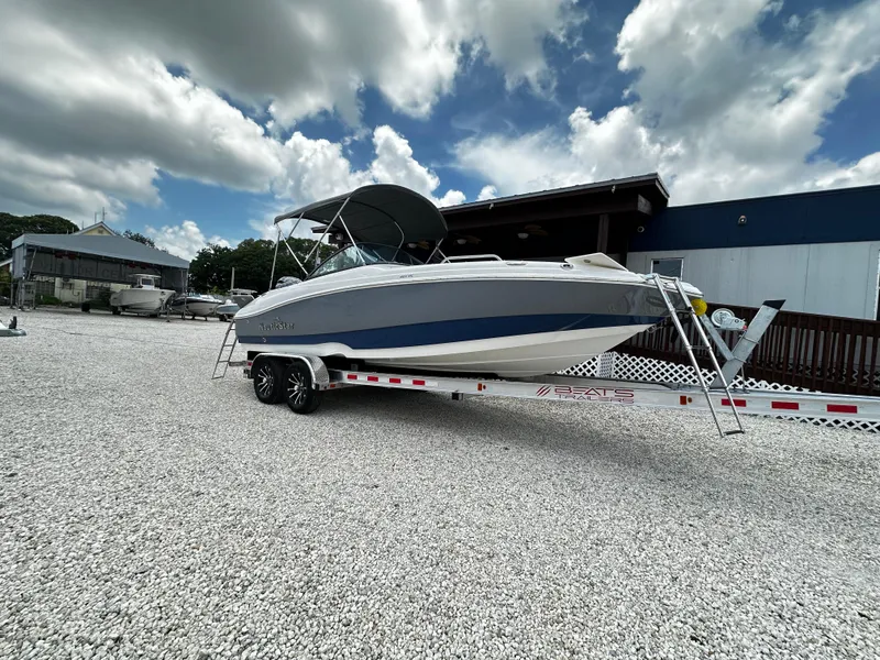 Slide: The Image of 2024 NauticStar 203 DC boat on trailer, parked outdoors under cloudy sky. - 0