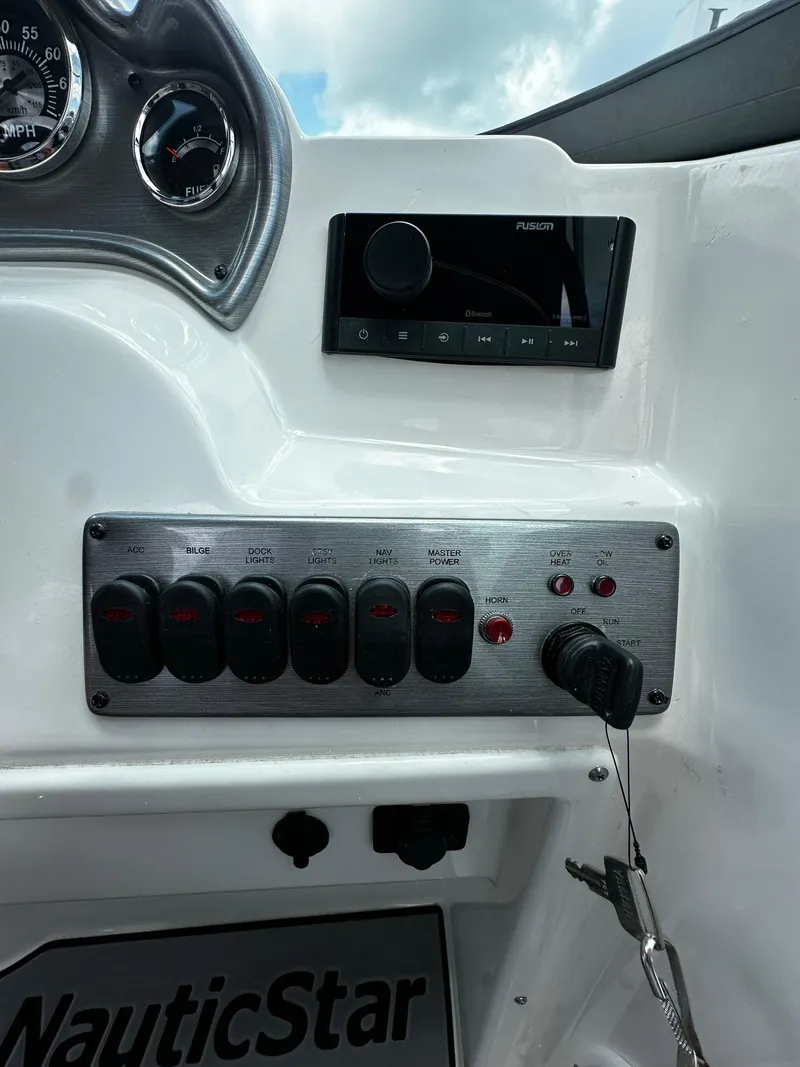 Slide: The Image of 2024 NauticStar 203 DC dashboard with controls and stereo system. - 13