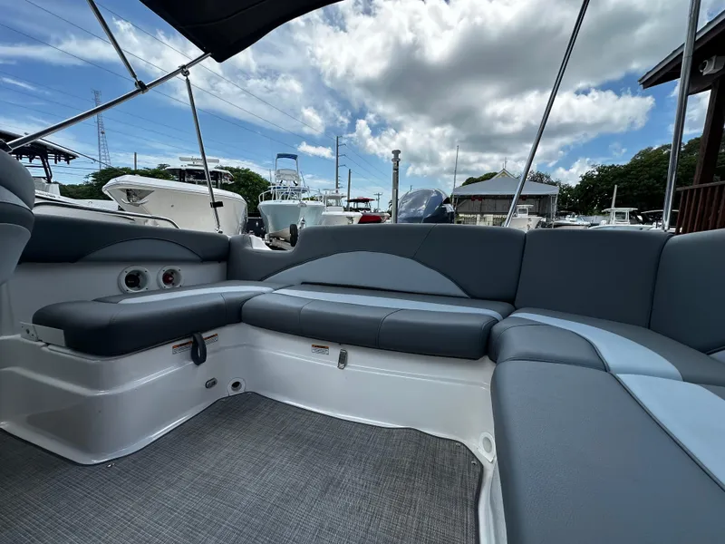 Slide: The Image of 2024 NauticStar 203 DC boat interior with gray seating and canopy under a blue sky. - 16