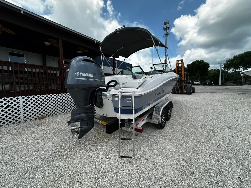 Slide: The Image of 2024 NauticStar 203 DC boat with Yamaha engine on gravel lot. - 2