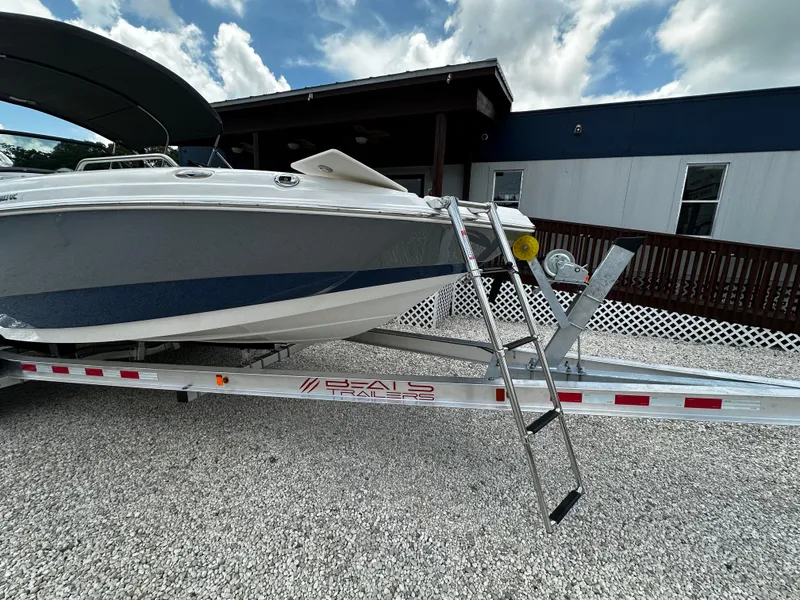 Slide: The Image of 2024 NauticStar 203 DC boat on trailer with ladder, parked on gravel. - 5