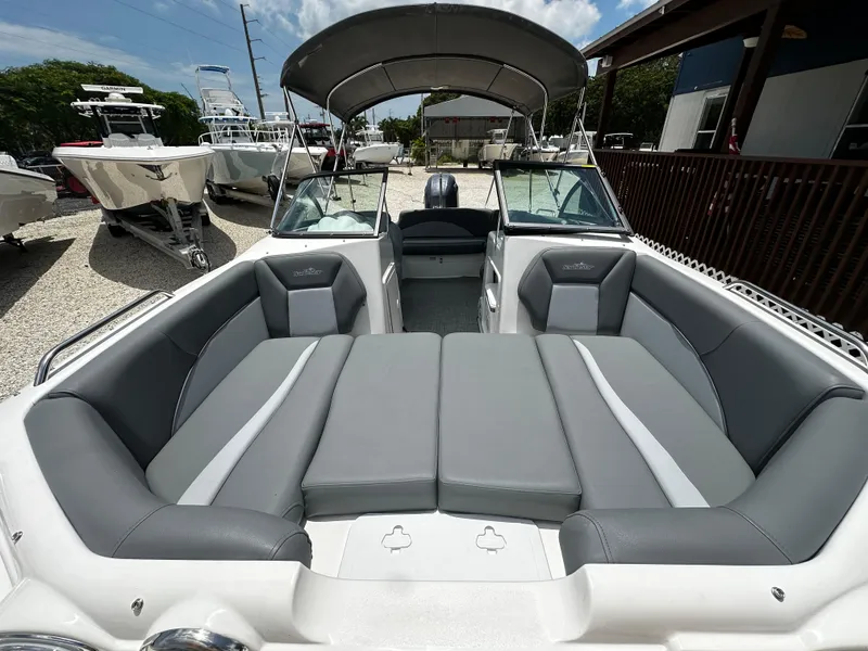 Slide: The Image of 2024 NauticStar 203 DC boat with spacious seating and canopy in a marina setting. - 7