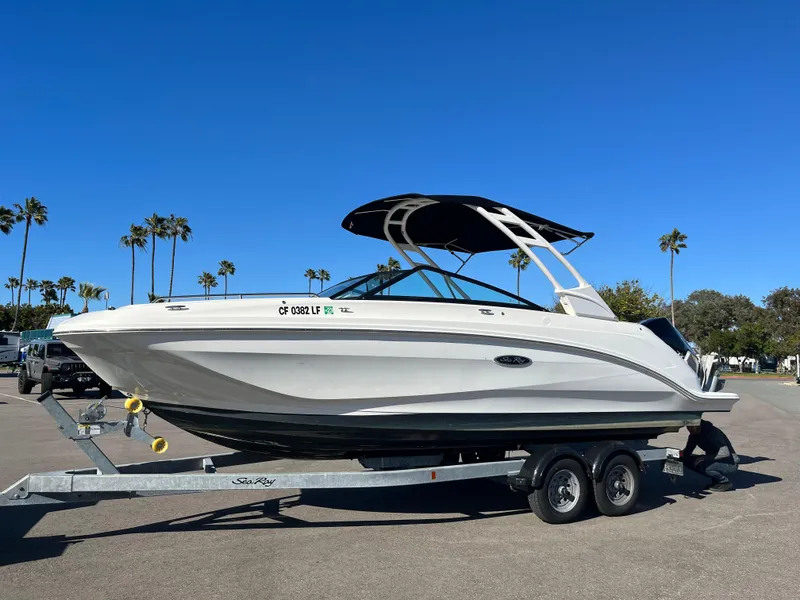 Slide: The Image of 2021 Sea Ray SDX 250 Outboard boat on trailer, parked outdoors under clear blue sky. - 2
