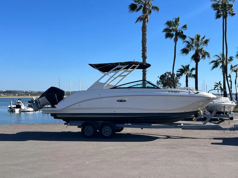 Slide: The Image of 2021 Sea Ray SDX 250 Outboard boat on trailer by waterfront, palm trees in background. - 6