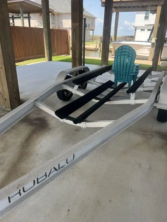 Slide: The Image of 2023 Robalo R242 boat trailer with a teal chair, parked under a wooden shelter. - 37