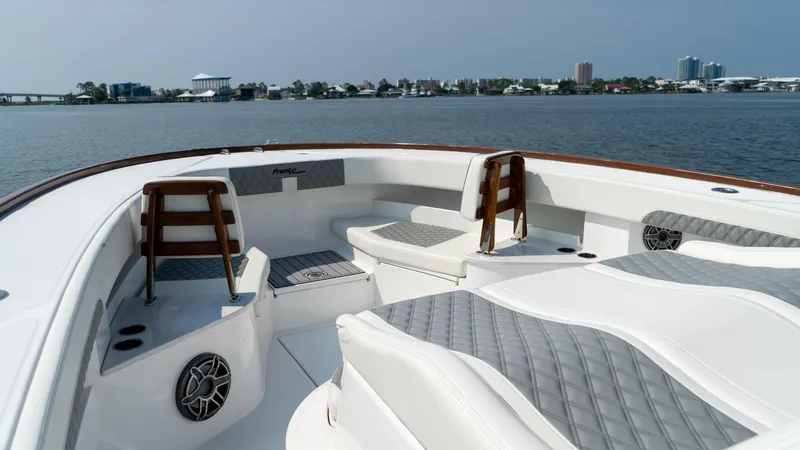Slide: The Image of 2023 Front Runner 47 Center Console boat interior with seating and speakers on a calm waterway. - 30