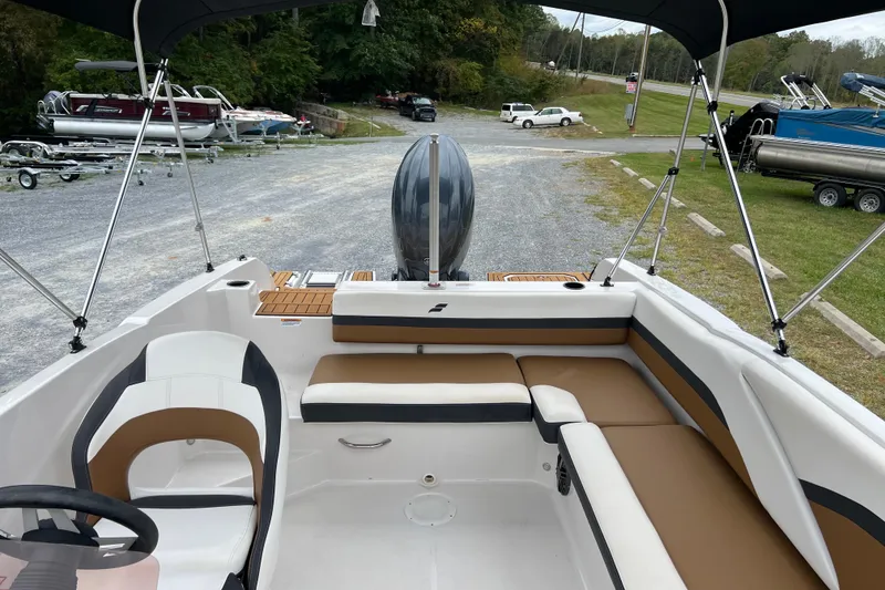 Slide: The Image of 2024 Starcraft SVX 211 OB boat interior with seating and outboard motor, parked outdoors. - 14