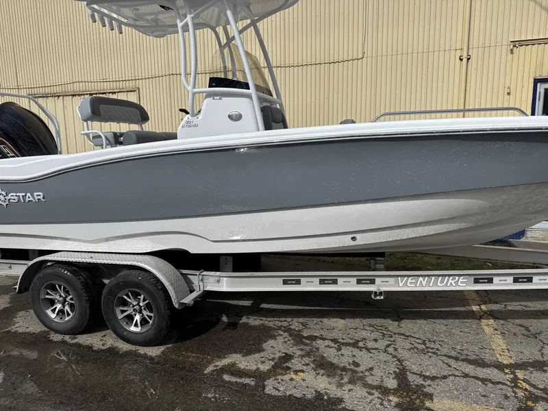 Slide: The Image of 2025 NauticStar 231 Hybrid boat on a Venture trailer, parked outdoors. - 2