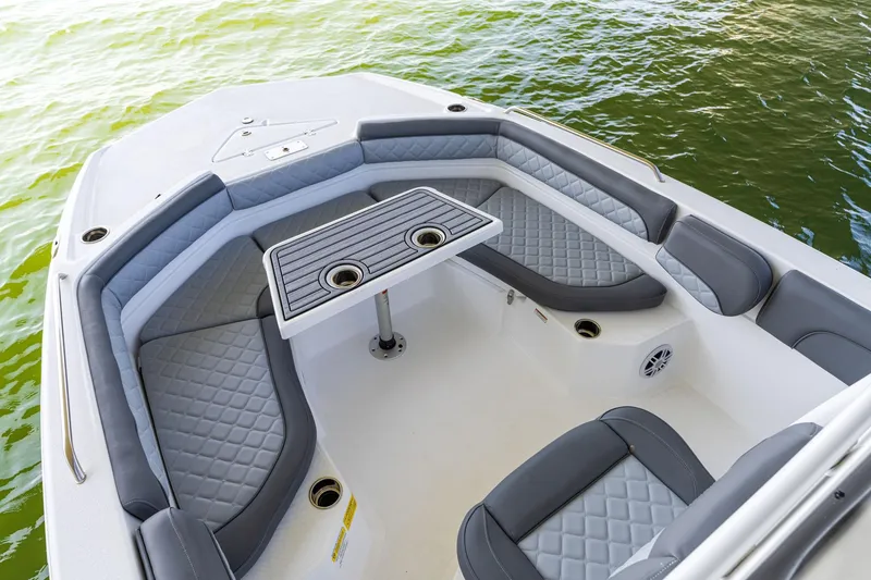 Slide: The Image of 2025 NauticStar 231 Hybrid boat interior with cushioned seating and table on water. - 22