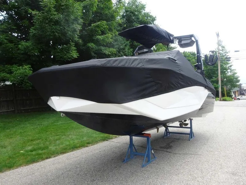 Slide: The Image of 2025 Nautique G23 boat covered, elevated on stands, parked on a residential street. - 4
