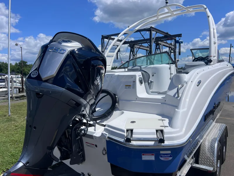 Slide: The Image of 2025 NauticStar 243 DC Deck boat with powerful outboard motor, docked under a clear sky. - 2