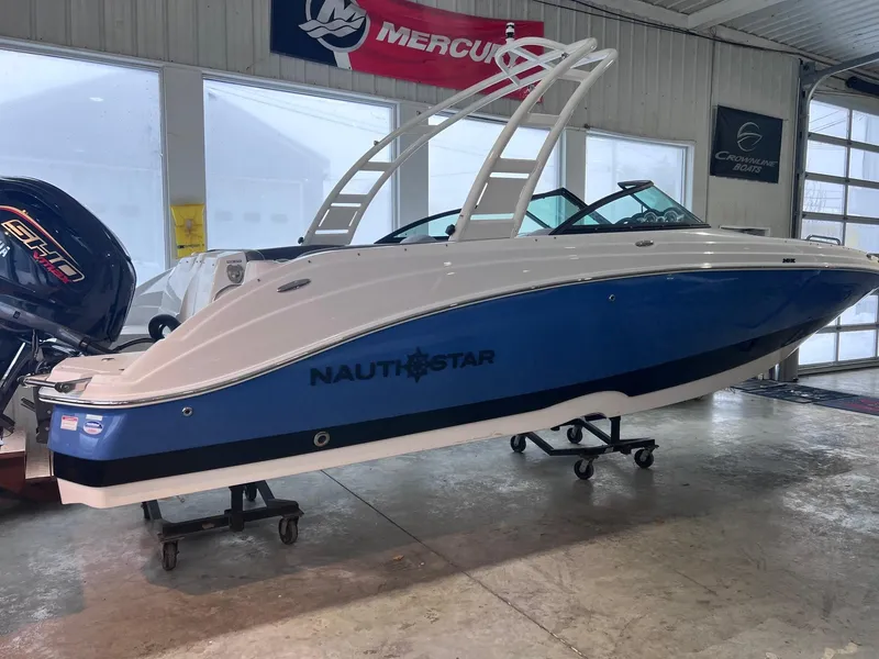 Slide: The Image of 2025 NauticStar 243 DC Deck boat in showroom, blue and white design. - 3