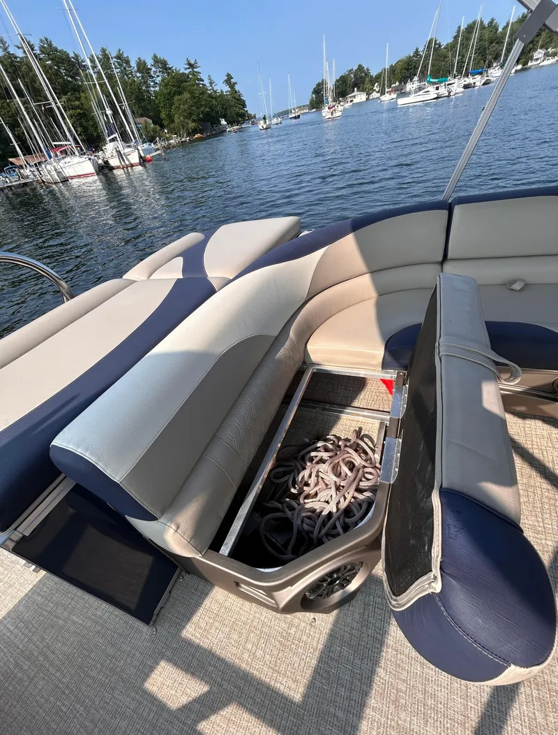 Slide: The Image of 2024 Avalon LSZ Cruise 25' boat interior with storage compartment, docked in a scenic marina. - 13