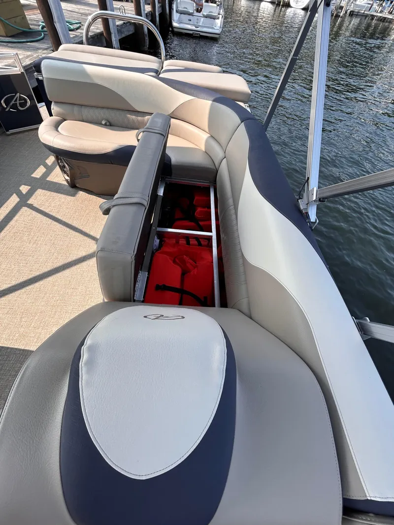 Slide: The Image of 2024 Avalon LSZ Cruise 25' boat interior with open storage compartment, docked by the water. - 14