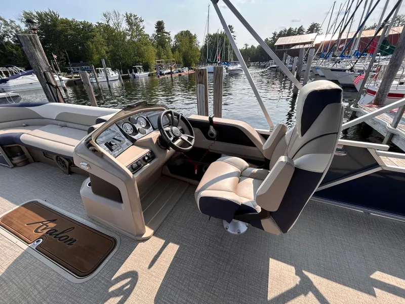 Slide: The Image of 2024 Avalon LSZ Cruise 25' boat interior with steering wheel and seating at marina. - 19