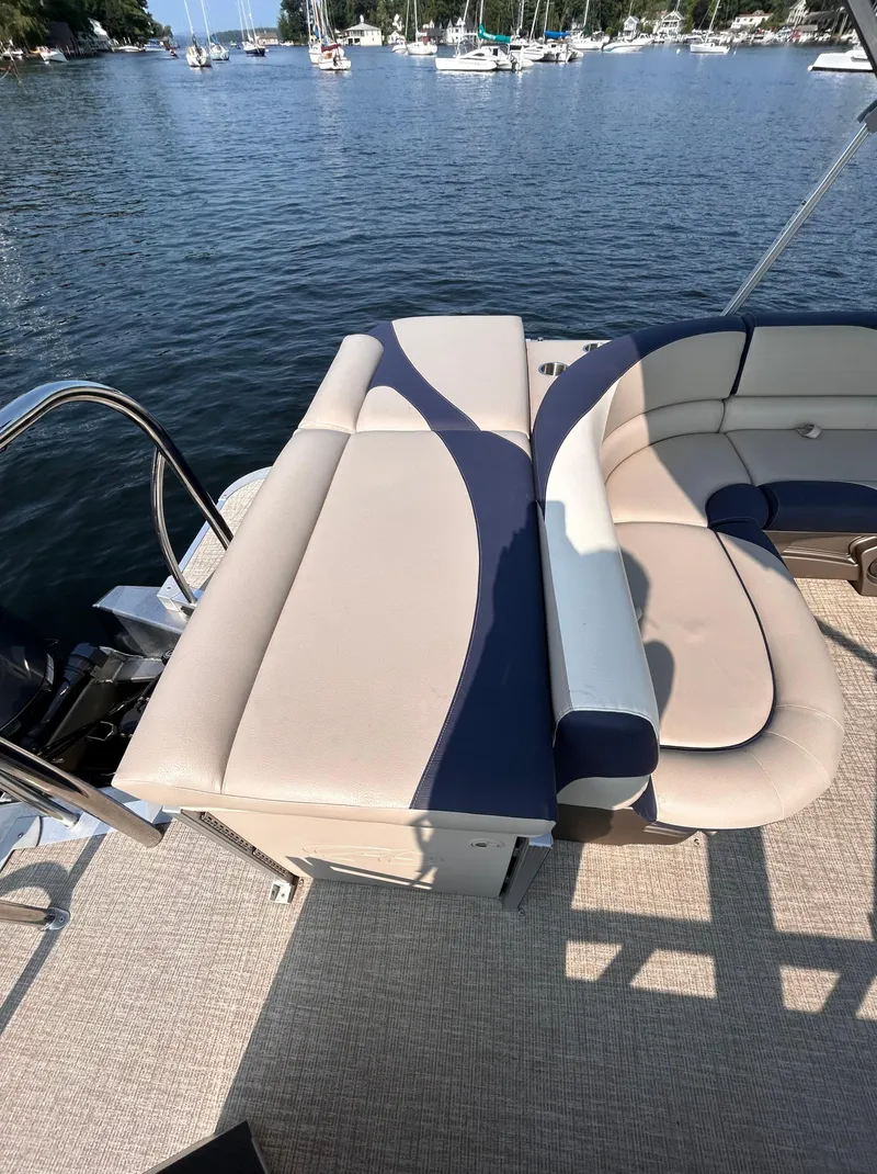 Slide: The Image of 2024 Avalon LSZ Cruise 25' boat interior with beige and blue seating, docked on a serene lake. - 9