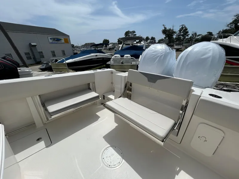 Slide: The Image of 2025 Sailfish 312 CC boat interior with foldable seating in a marina setting. - 25