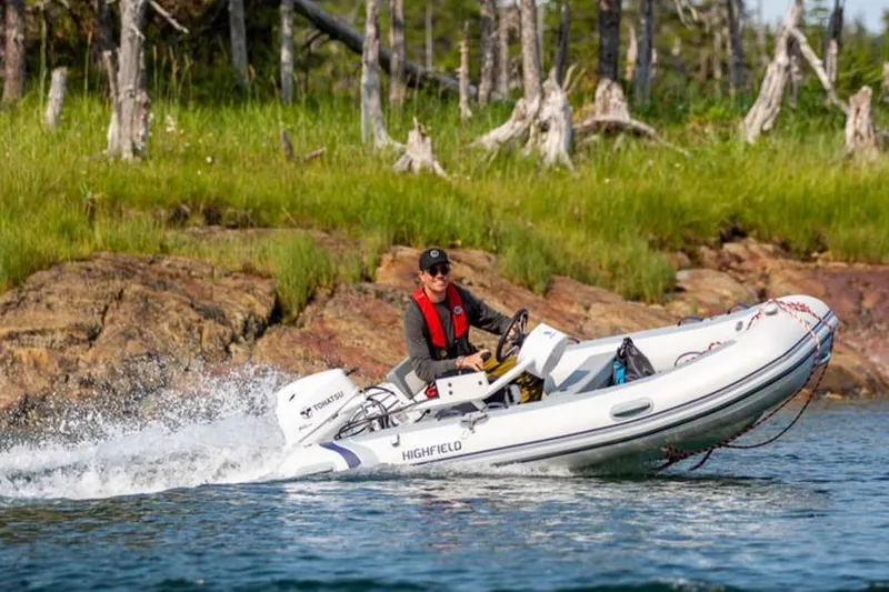 Slide: The Image of Person driving 2025 Highfield CL360 boat near rocky shoreline with trees. - 11