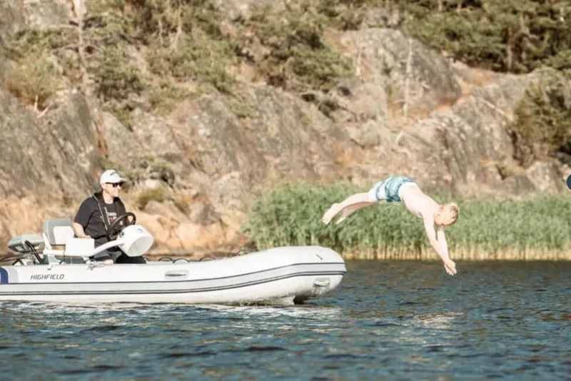 Slide: The Image of Man on Highfield CL380 boat, child diving into lake, rocky forest background. - 3