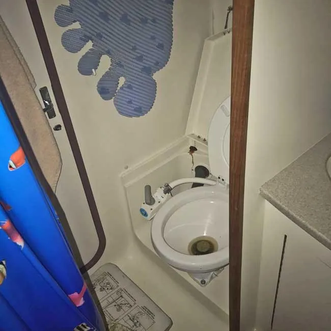 Slide: The Image of Compact marine bathroom in a 1999 Hunter 380 sailboat, featuring a toilet and shower curtain. - 14