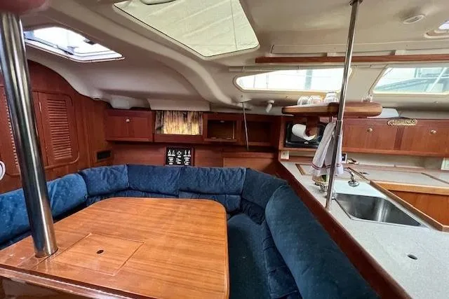 Slide: The Image of Interior of 1999 Hunter 380 sailboat with wooden dining area and blue seating. - 24