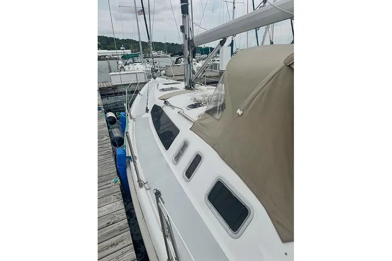 Slide: The Image of 1999 Hunter 380 sailboat docked at marina, featuring beige canopy and sleek design. - 28