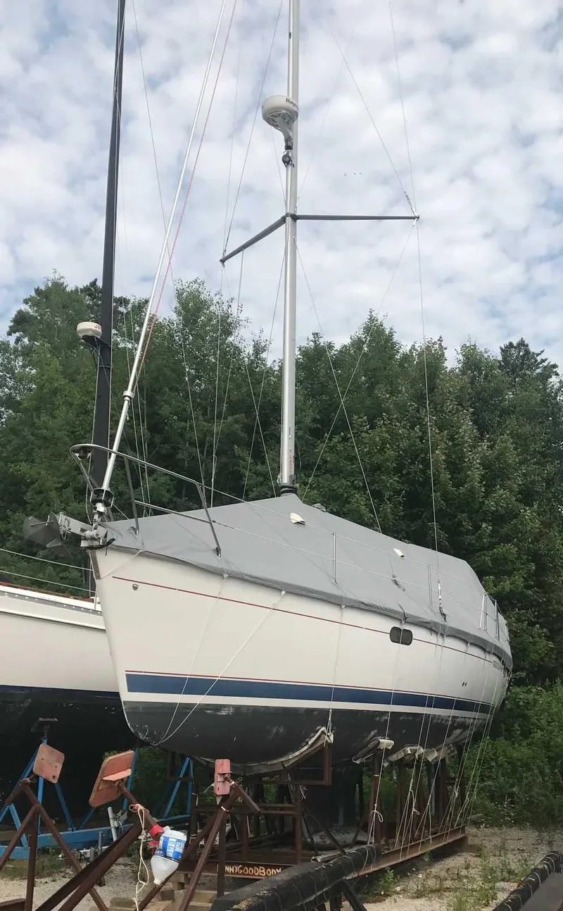 Slide: The Image of 1999 Hunter 380 sailboat on dry dock, surrounded by trees and cloudy sky. - 3