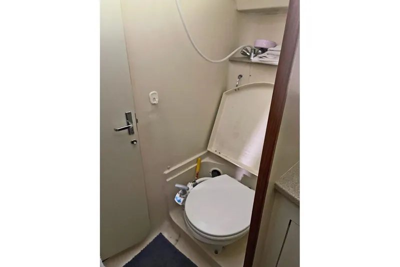 Slide: The Image of Compact bathroom in a 1999 Hunter 380 sailboat, featuring a toilet and storage shelves. - 37