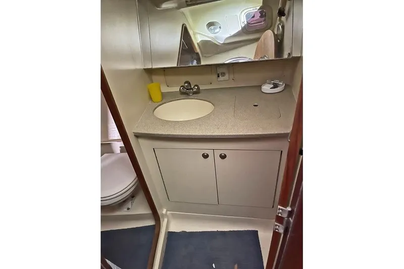Slide: The Image of 1999 Hunter 380 yacht bathroom with sink, mirror, and storage cabinets. - 38
