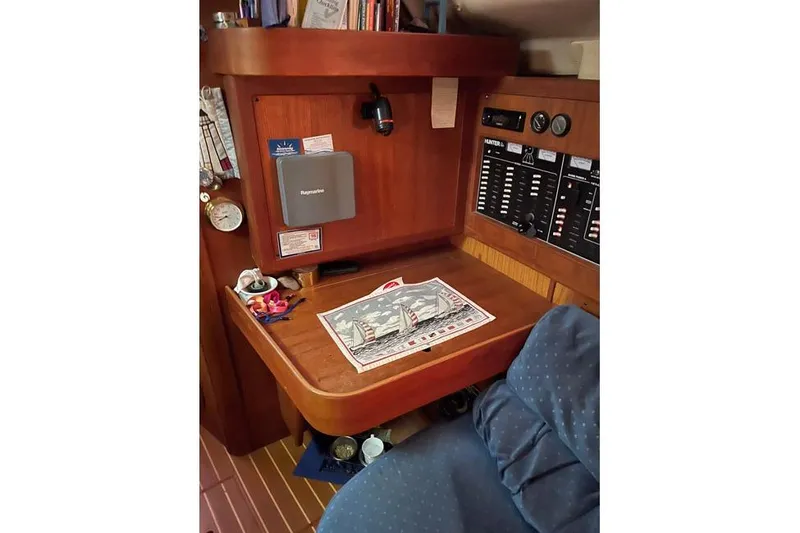 Slide: The Image of Navigation station inside a 1999 Hunter 380 sailboat, featuring control panels and nautical chart. - 45