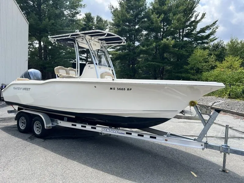 Slide: The Image of 2019 Key West 239FS boat on trailer, parked outdoors near trees. - 1