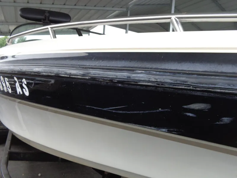 Slide: The Image of 1998 Malibu Sunsetter VLX boat with visible hull scratches under a covered area. - 3