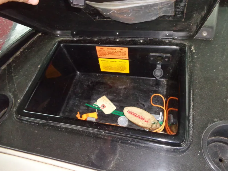 Slide: The Image of Open storage compartment in 1998 Malibu Sunsetter VLX boat with safety warnings and items inside. - 44