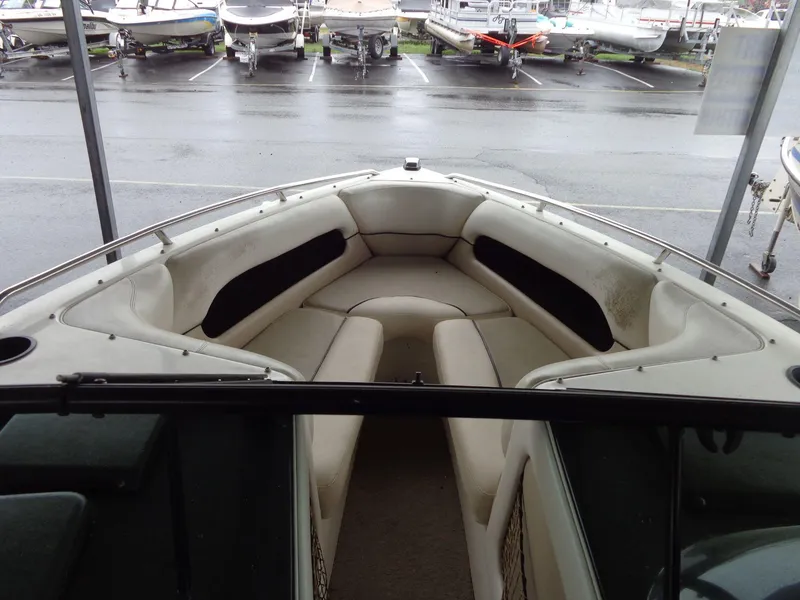 Slide: The Image of 1998 Malibu Sunsetter VLX boat interior with white seating, parked among other boats. - 48