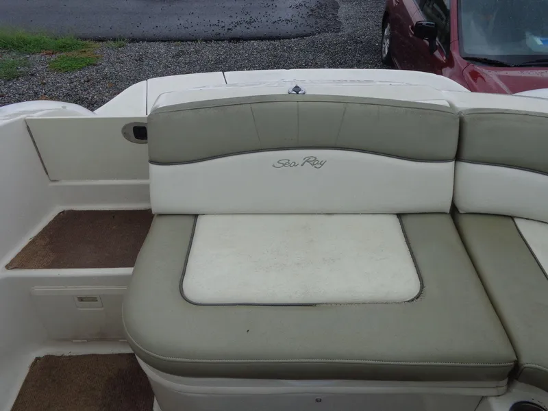 Slide: The Image of 2007 Sea Ray 200 Sundeck boat seating area with logo, parked on gravel. - 25