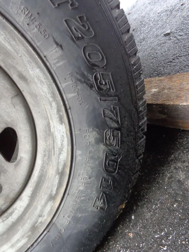 Slide: The Image of Close-up of a trailer tire with size markings, wet pavement background. - 9