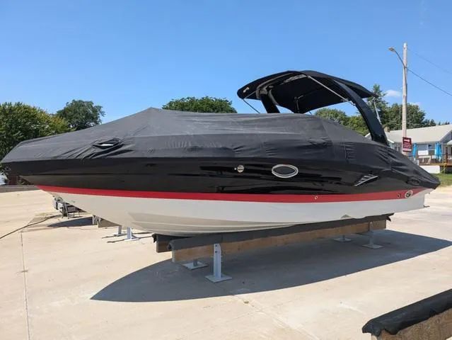 Slide: The Image of 2022 Crownline 255 SS boat with black cover on a trailer, outdoors. - 24