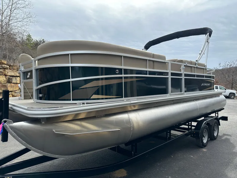 Slide: The Image of 2024 Starcraft LX 22 F pontoon boat on trailer, parked outdoors. - 4