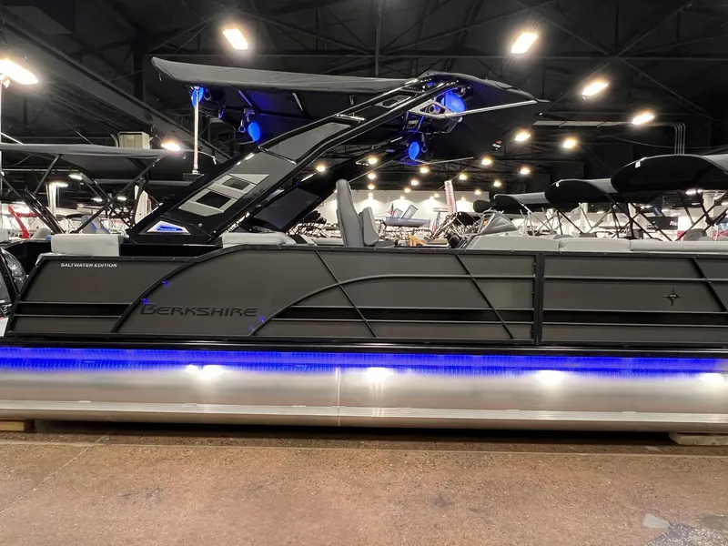 Slide: The Image of 2025 Berkshire 25RFX Roswell Arch STS Tritoon with blue LED lights on display indoors. - 34