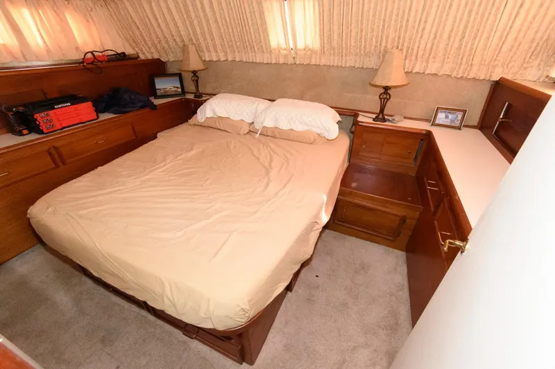 Slide: The Image of 1985 Ocean Yachts 46 Aft Cabin Motor Yacht bedroom with double bed, wooden cabinetry, and lamps. - 20