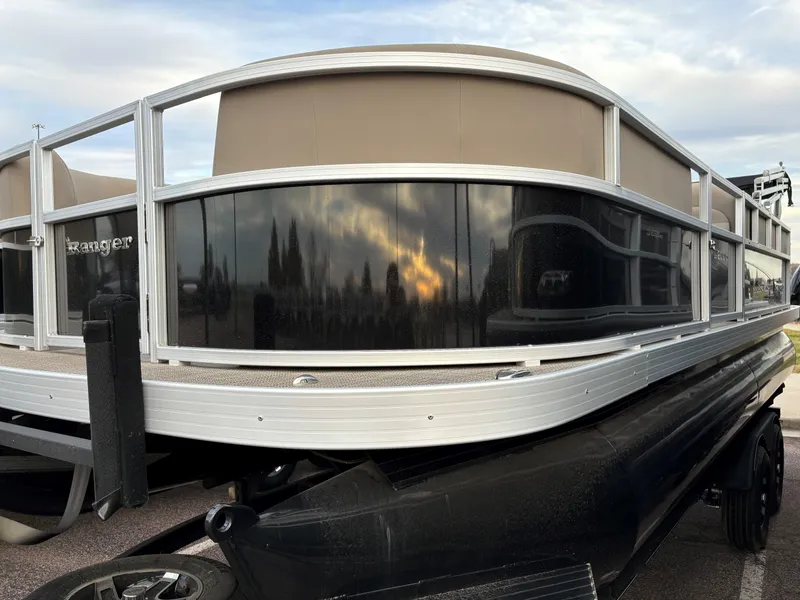 Slide: The Image of 2024 Ranger Reata 200C pontoon boat with sleek design and reflective panels. - 2