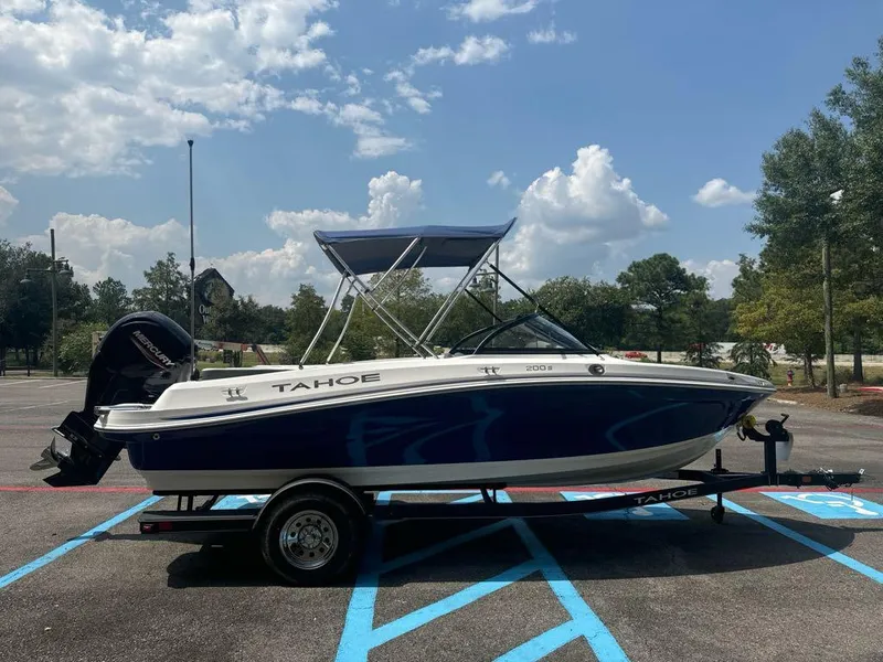 Slide: The Image of 2024 Tahoe 200 S boat on trailer in parking lot, under clear sky. - 2
