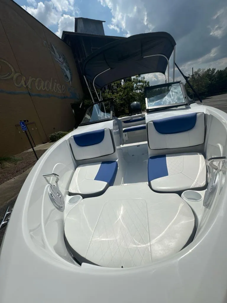 Slide: The Image of 2024 Tahoe 200 S boat with spacious seating and canopy under a partly cloudy sky. - 4