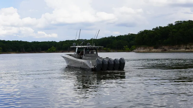 Slide: The Image of 2021 HCB 53 boat with multiple engines cruising on a scenic lake. - 3
