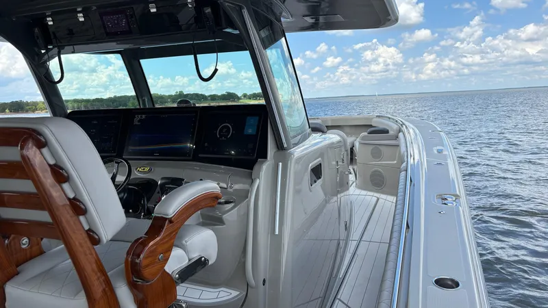 Slide: The Image of 2021 HCB 53 boat interior with helm, wooden accents, and ocean view. - 35