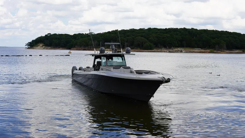 Slide: The Image of 2021 HCB 53 boat cruising on a calm lake with forested shoreline. - 5